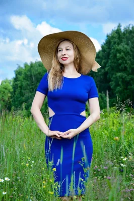 Mulher de vestido azul e chapéu em campo