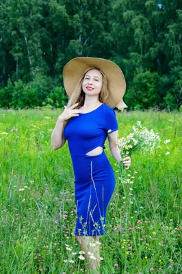 Mulher com vestido azul e chapéu em campo